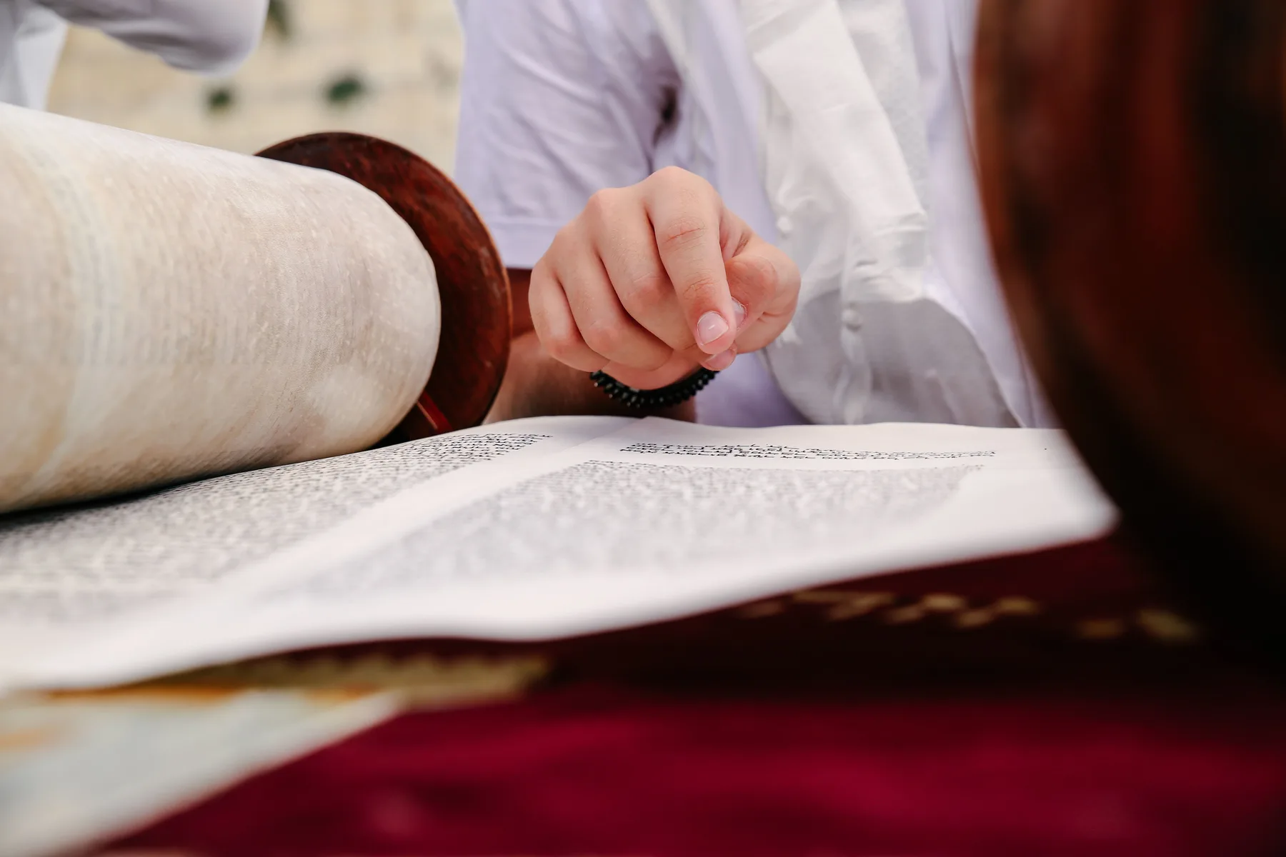 A hand following the text in a Torah scroll